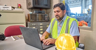 Hardhat worker looking at laptop