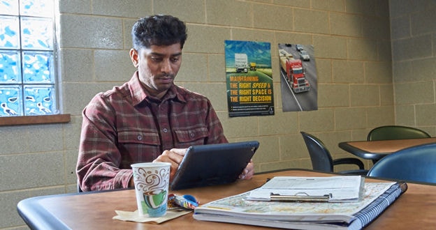 CDL Driver doing trip planning at truck stop using a tablet and map