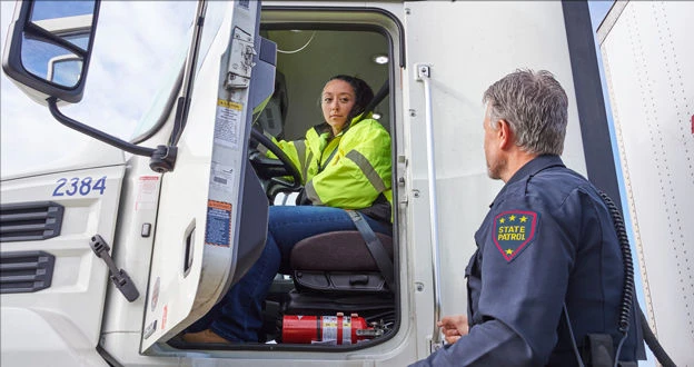 Driver sitting in truck talking to officer standing outside the truck