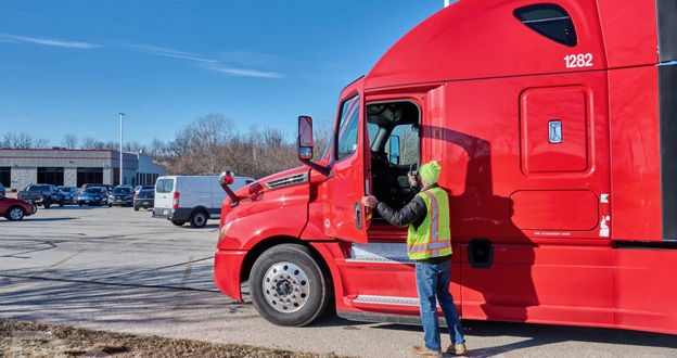 Driver opening cab door on red semi cab