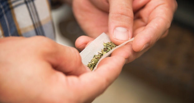 Rolling marijuana (two hands holding paper with marijuana)